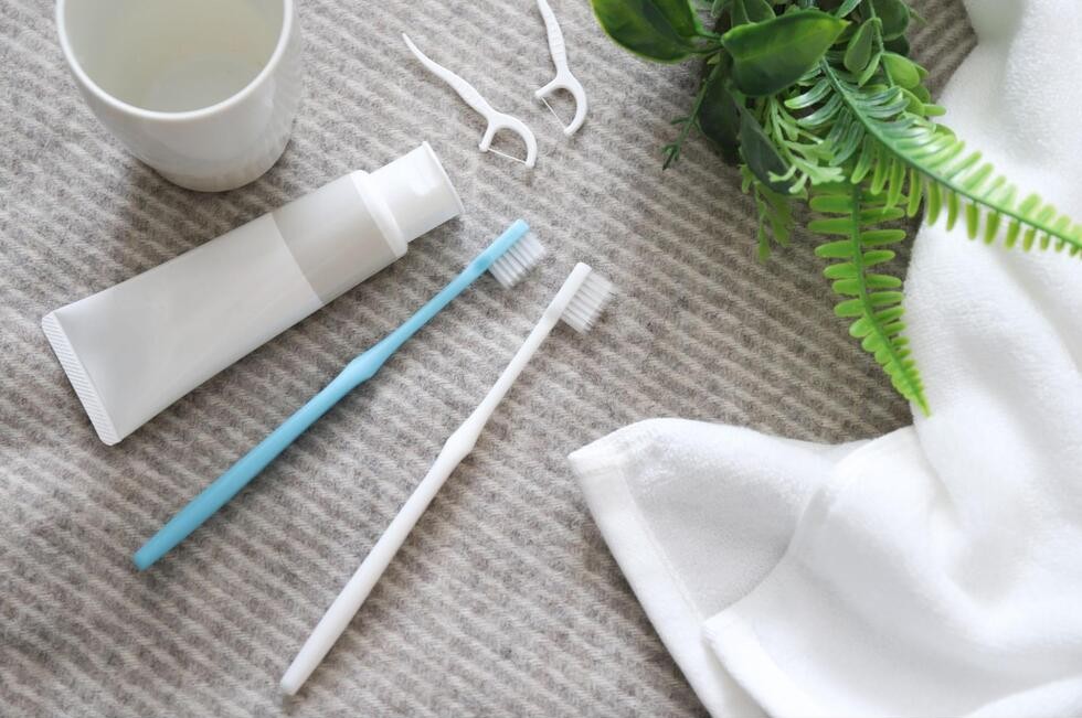 歯ブラシと歯磨き粉、デンタルフロス、コップが並んでいる